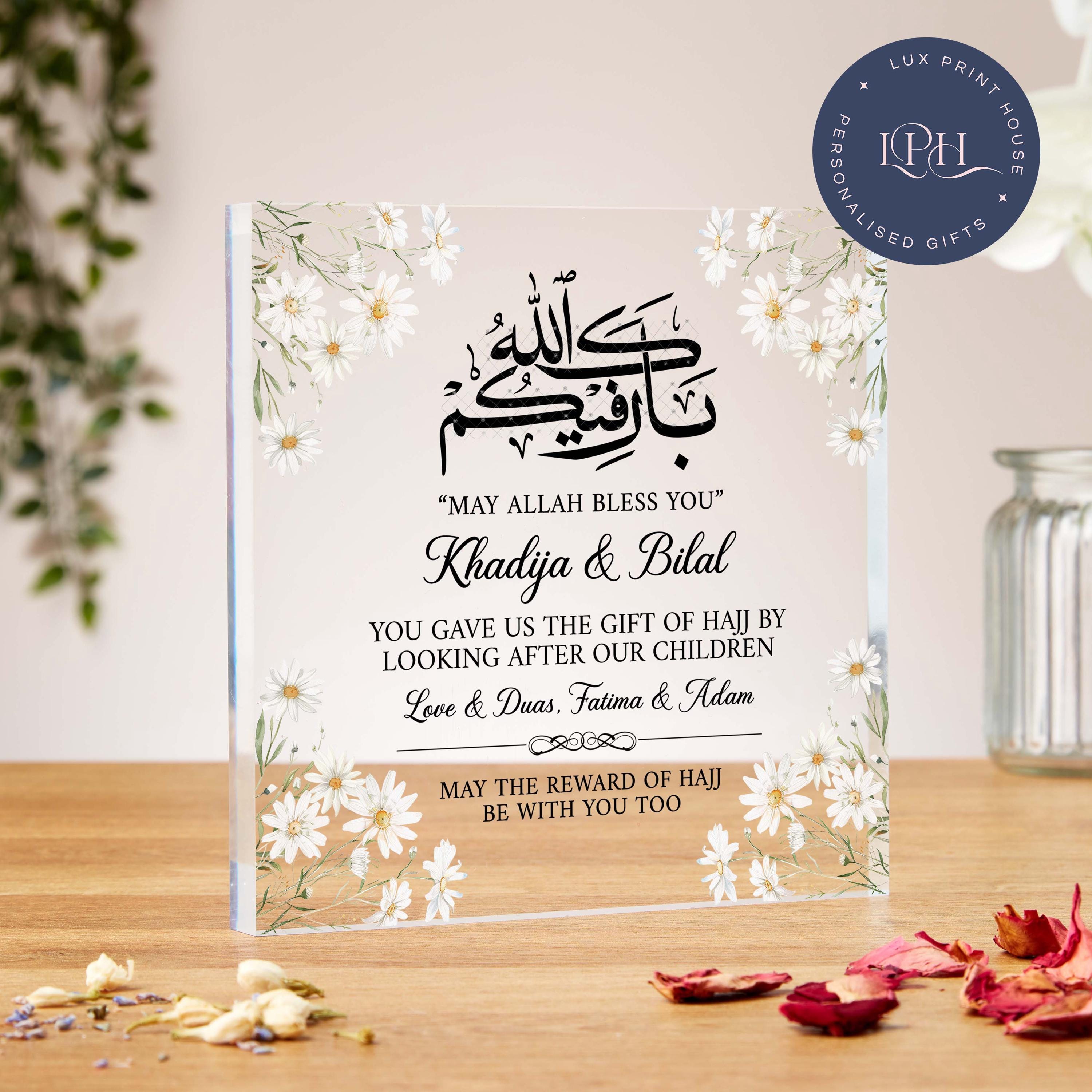 
A floral acrylic block featuring white daisies and Arabic calligraphy with the phrase “May Allah bless you.” Designed as a thank you gift for those who cared for children during Hajj, the plaque includes space for custom names and a personalised message. The phrase “May the reward of Hajj be with you too” is printed along the bottom, making it a heartfelt and faith-filled gesture of gratitude.