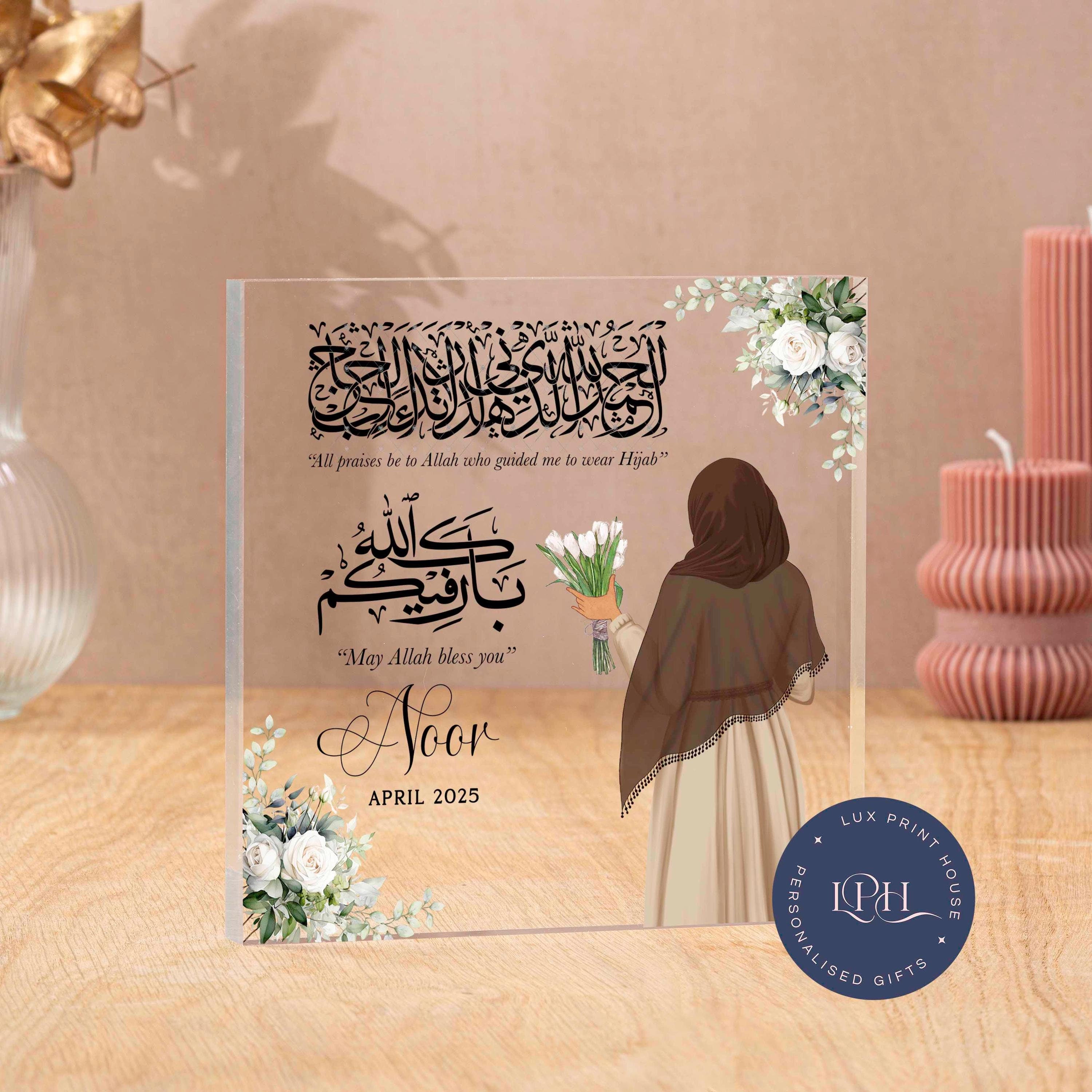 Personalised acrylic block featuring custom faceless art of a woman in hijab holding flowers, adorned with floral accents and meaningful Islamic quotes: “All praises be to Allah who guided me to wear Hijab” and “May Allah bless you.” Includes personalised name and date, making it a heartfelt keepsake for celebrating a hijab journey, Islamic milestone, or spiritual gift.